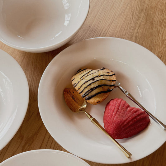 White Askew porcelain bowls and plate holding heart-shaped madeleines with gold and silver spoons.