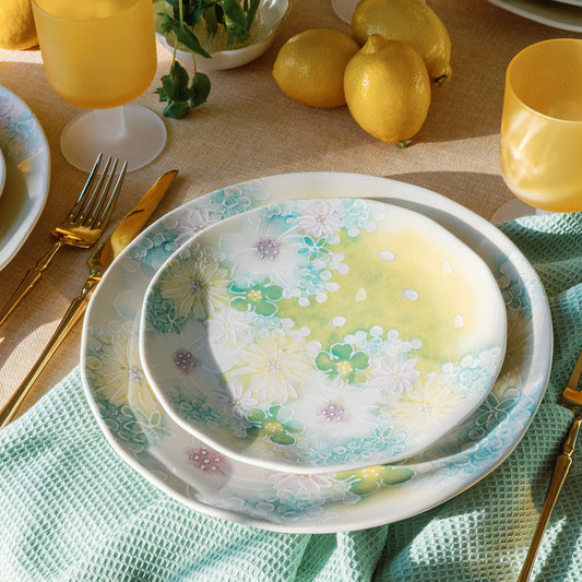 Watercolor Meadow floral plates styled with yellow glasses, lemons and ranunculus on a mint cloth, table scene.