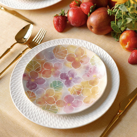 Floral-patterned plates on a table with fruit and cutlery