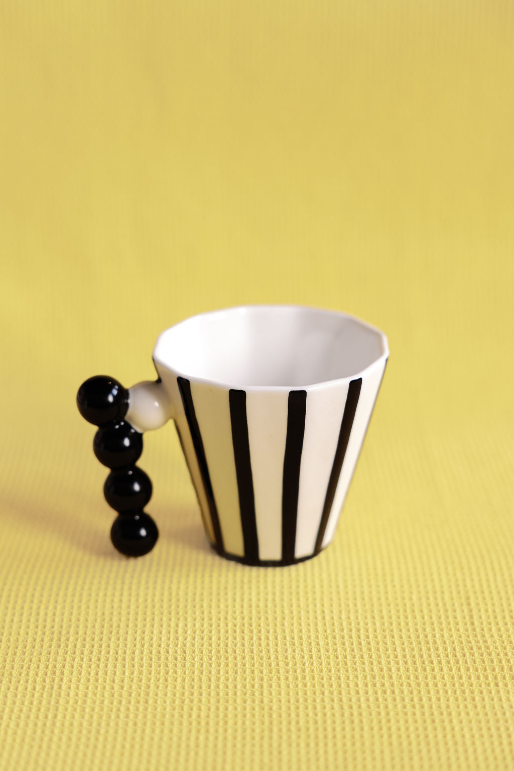 Striped mug with black handle on a yellow background