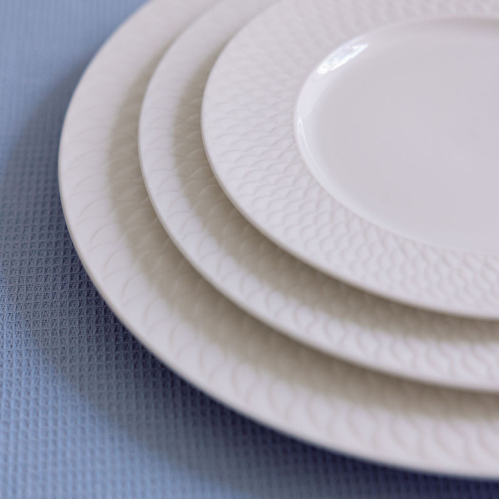 Stack of white ceramic plates on a textured blue surface