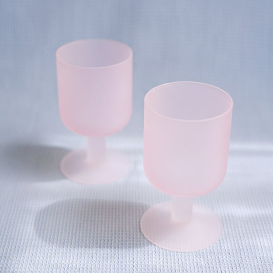 Two pink goblets with white bases on a light gray background