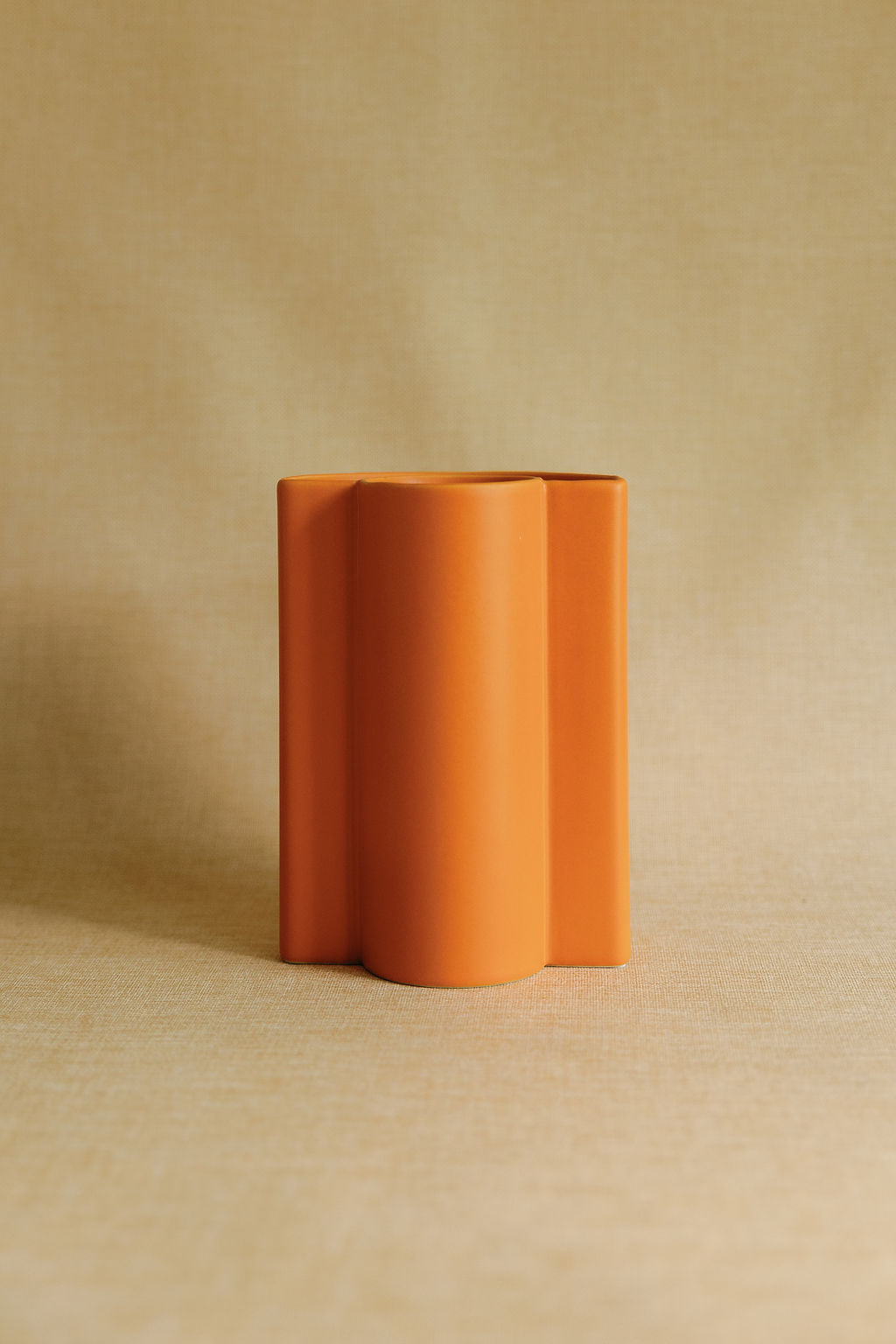 Orange ceramic vase on a beige background