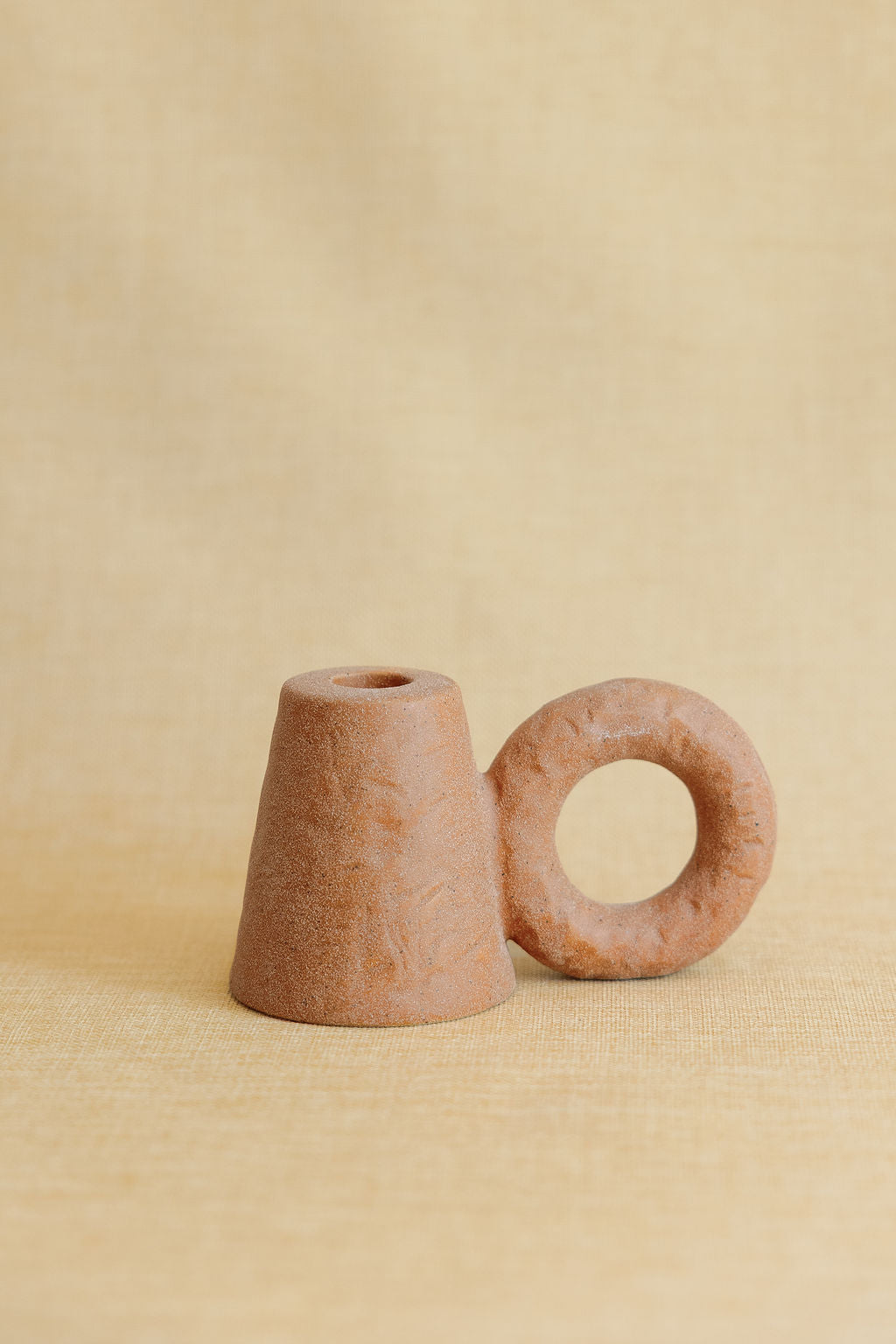Two terracotta candle holders on a beige background