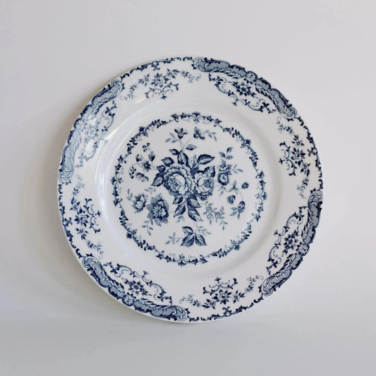 A white ceramic plate with a navy floral border pattern, displayed against a white background.