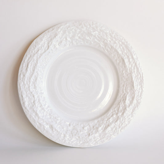 White Alpine Snow porcelain dinner plate with textured crackled rim and swirled center on a pale background.