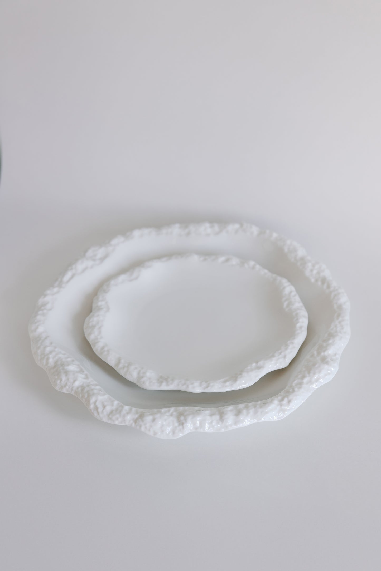 Two white Amalfi porcelain plates stacked to show size, both with textured organic rims on white.