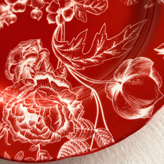 Close-up of white toile roses and blossoms on a deep red Cherry Chinoiserie porcelain dinner plate.