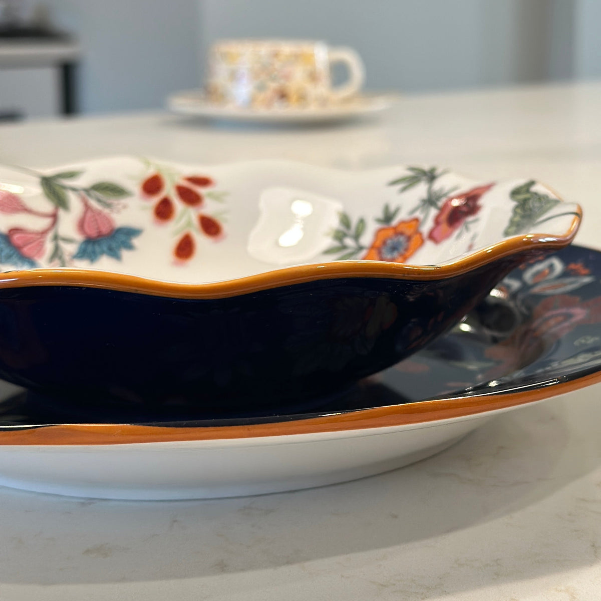 Azure Desert Floral scalloped salad bowl with navy and orange rim, styled on a kitchen counter.