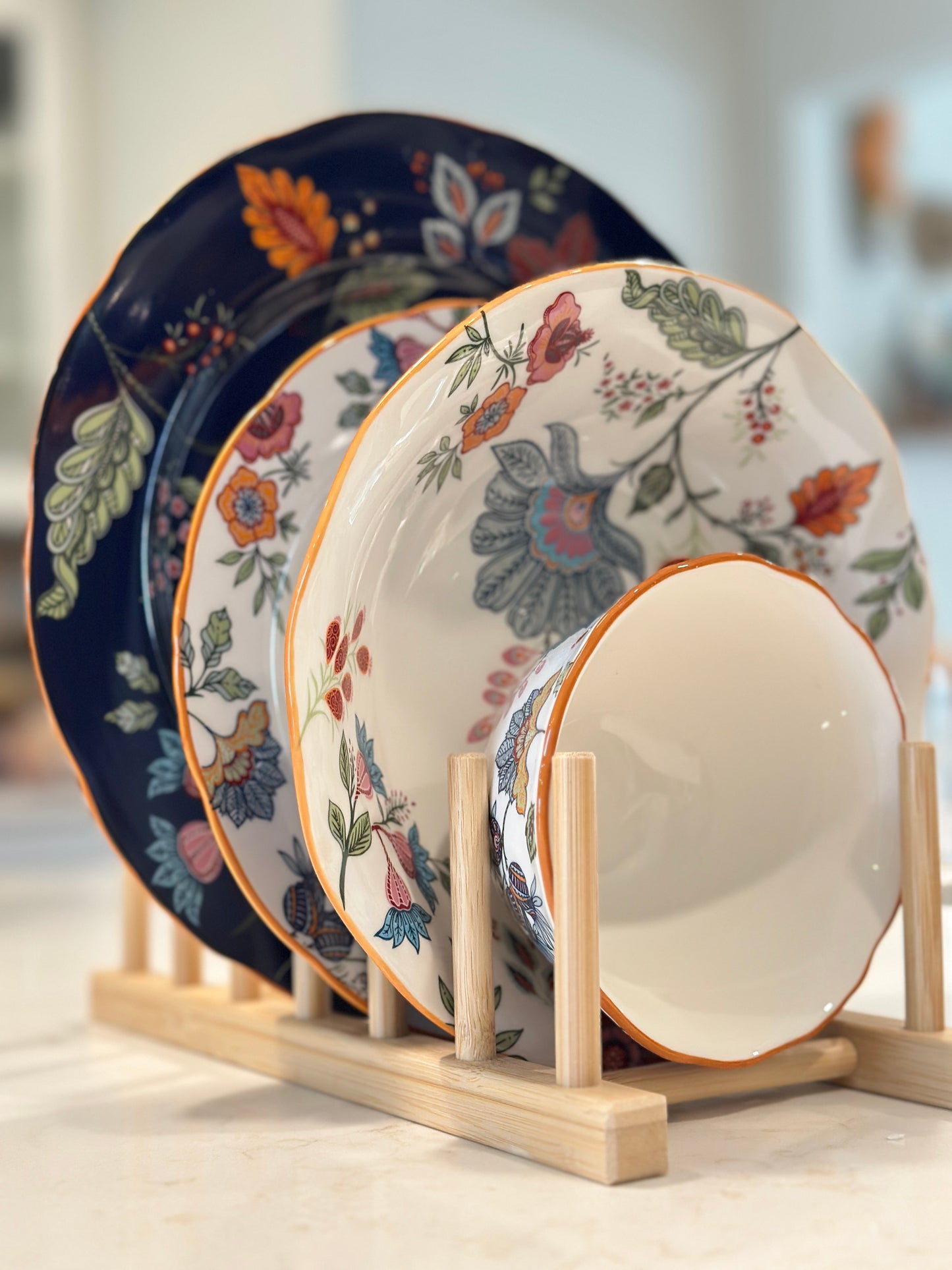 Azure Desert Floral plates and bowls in navy and floral prints displayed on a wooden rack.