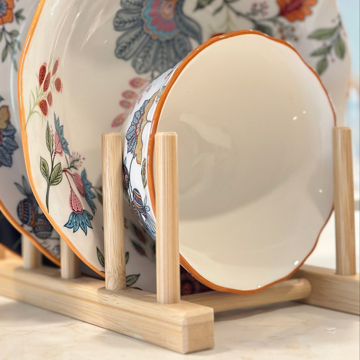 Azure Desert Floral plates and bowls in navy and floral prints displayed on a wooden rack.