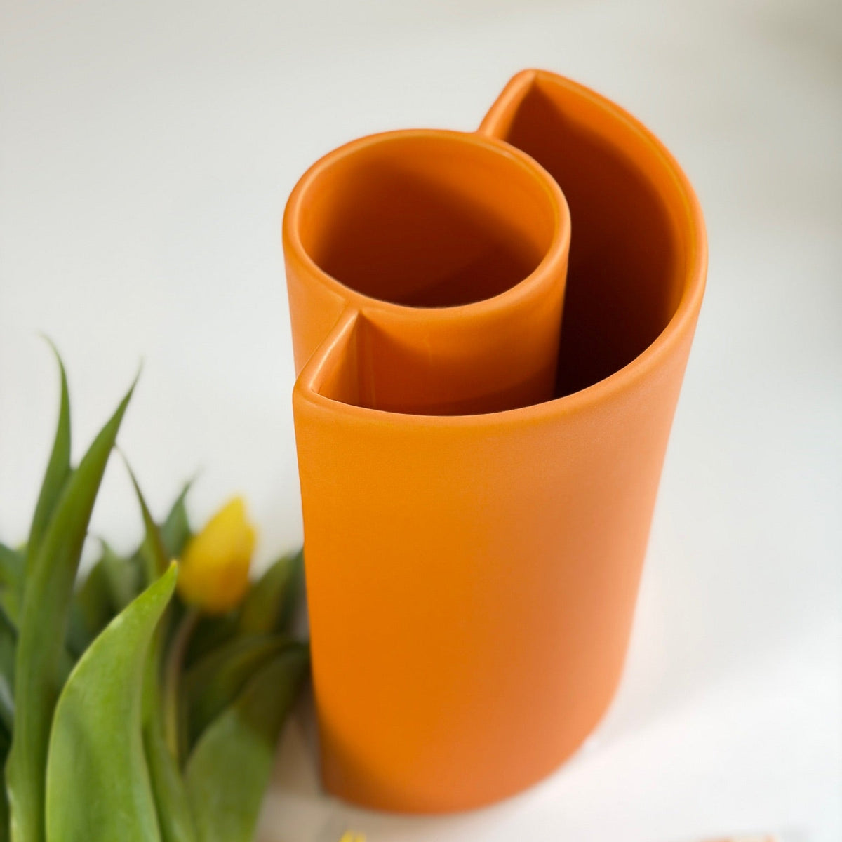 Orange Petal Ceramic Vase viewed from above showing the overlapping curled-petal opening, beside tulips.