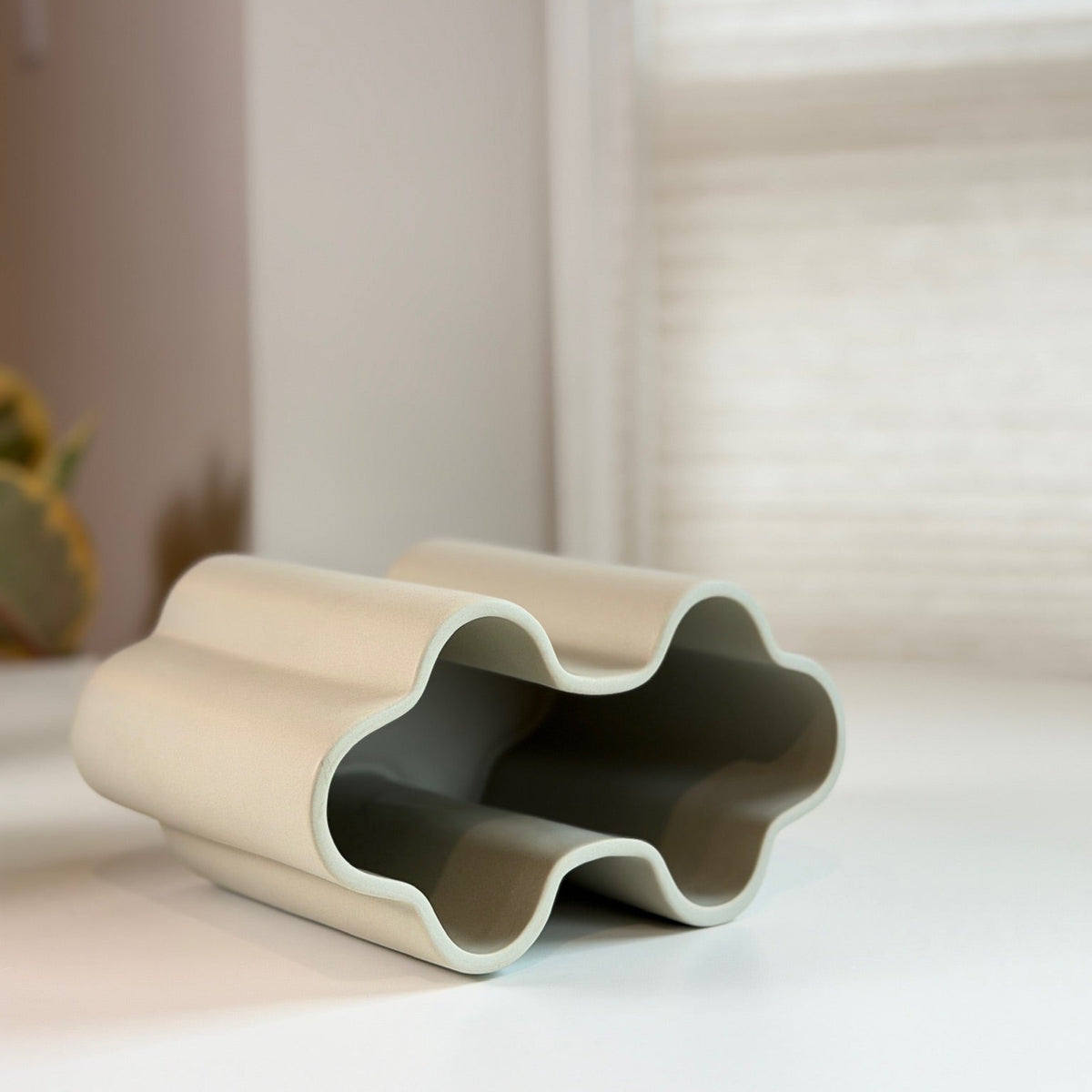 Cream Scalloped Ceramic Vase lying on its side showing the wavy cloud-shaped opening and gray interior.