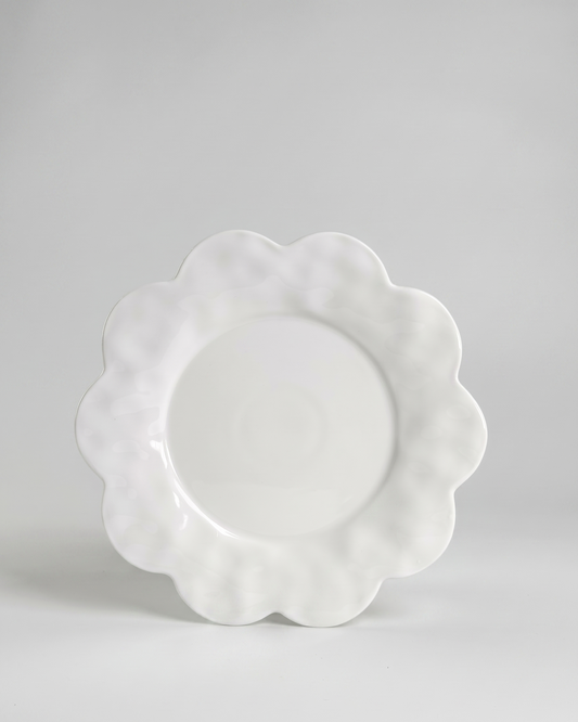 scalloped white saucer plate on gray background