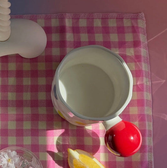 Table setting with teapots, cups, and a banana on a checkered tablecloth.
