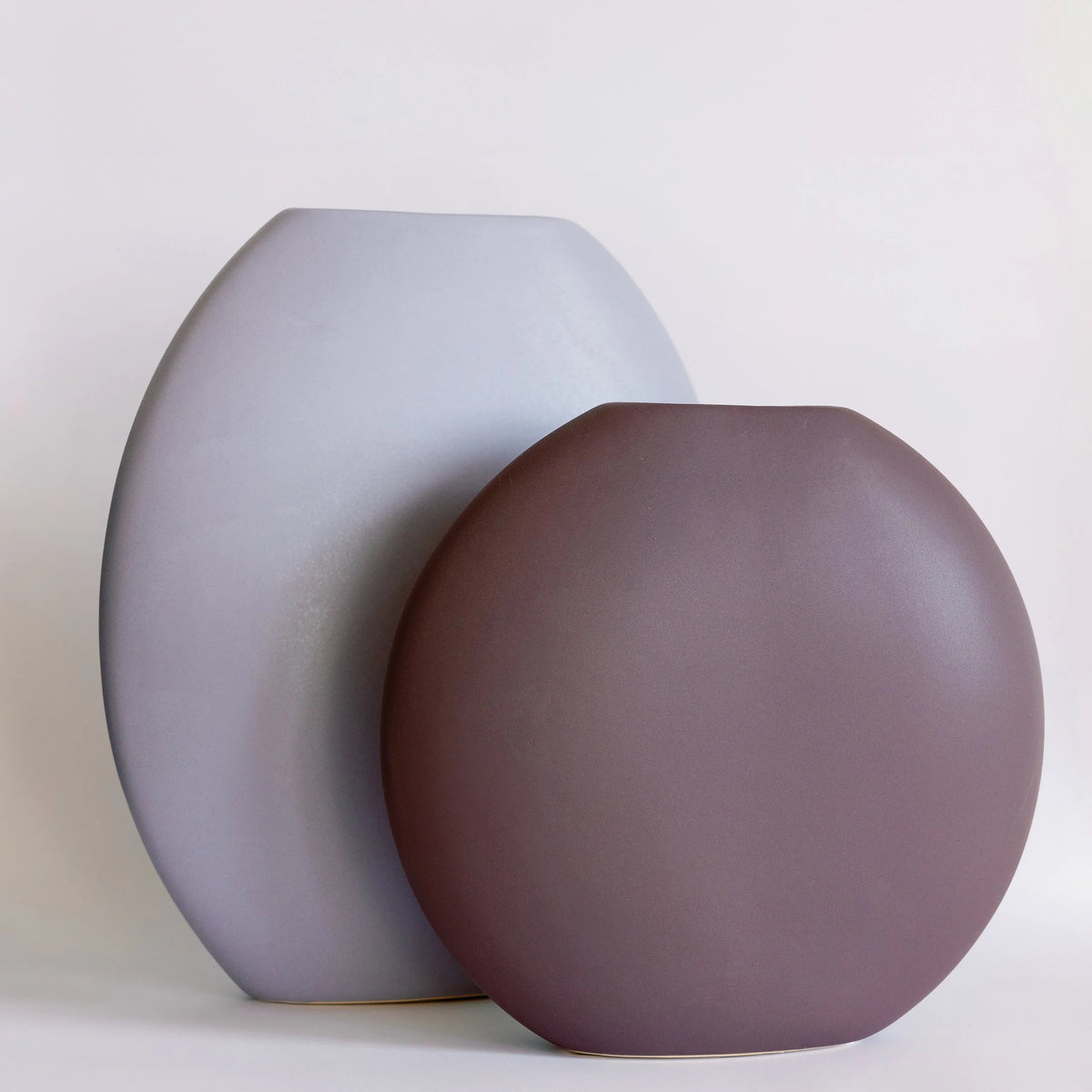 Luna ceramic vases in grey-blue and plum paired together, two rounded pebble forms side by side