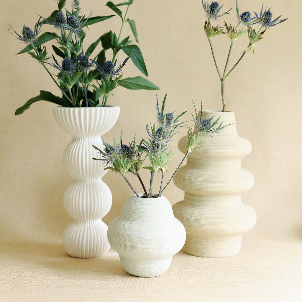 Cream Sediment ceramic bud vase with ribbed texture, grouped with two other neutral vases and thistle stems.