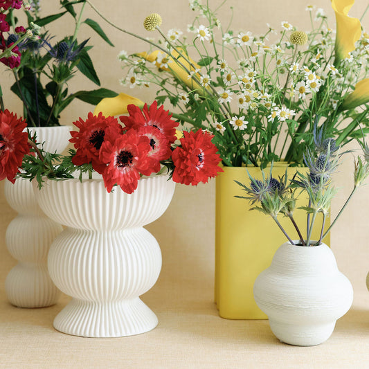 Vases with flowers on a beige surface