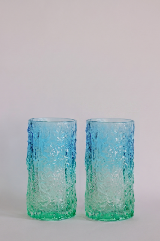 Two textured glass tumblers with a blue-to-green gradient, standing side by side against a light gray background.