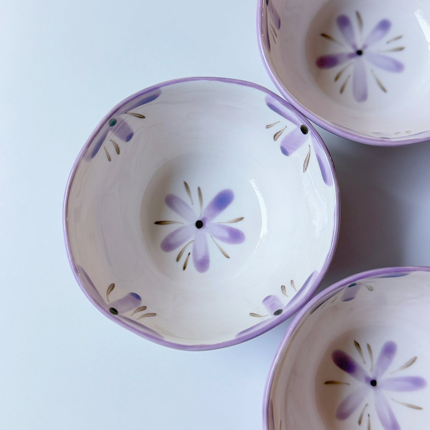 Three ceramic bowls with floral patterns on a light blue background
