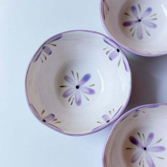 Three ceramic bowls with floral patterns on a light blue background