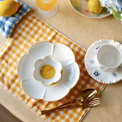 Table setting with lemons, a teacup, and checkered tablecloth.