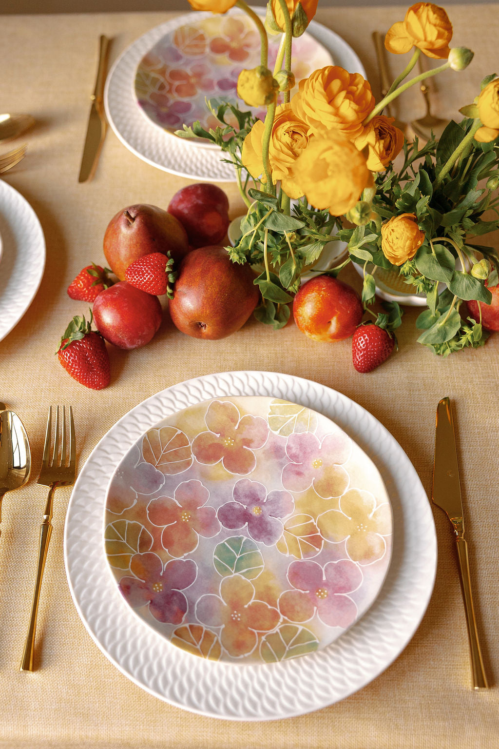 Watercolor Wildflower salad plate styled on a table with gold flatware, fruit, and yellow ranunculus.