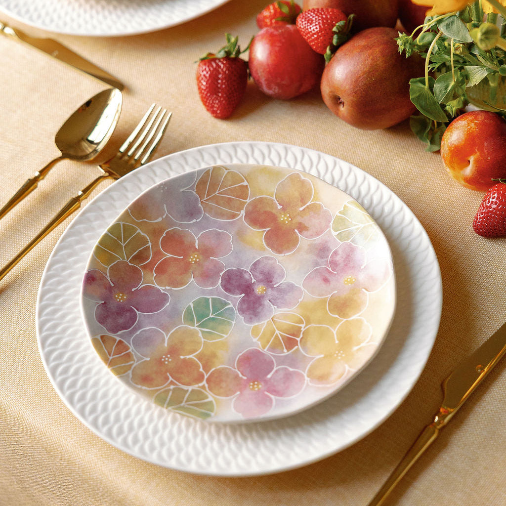 Floral-patterned plates on a table with fruit and cutlery