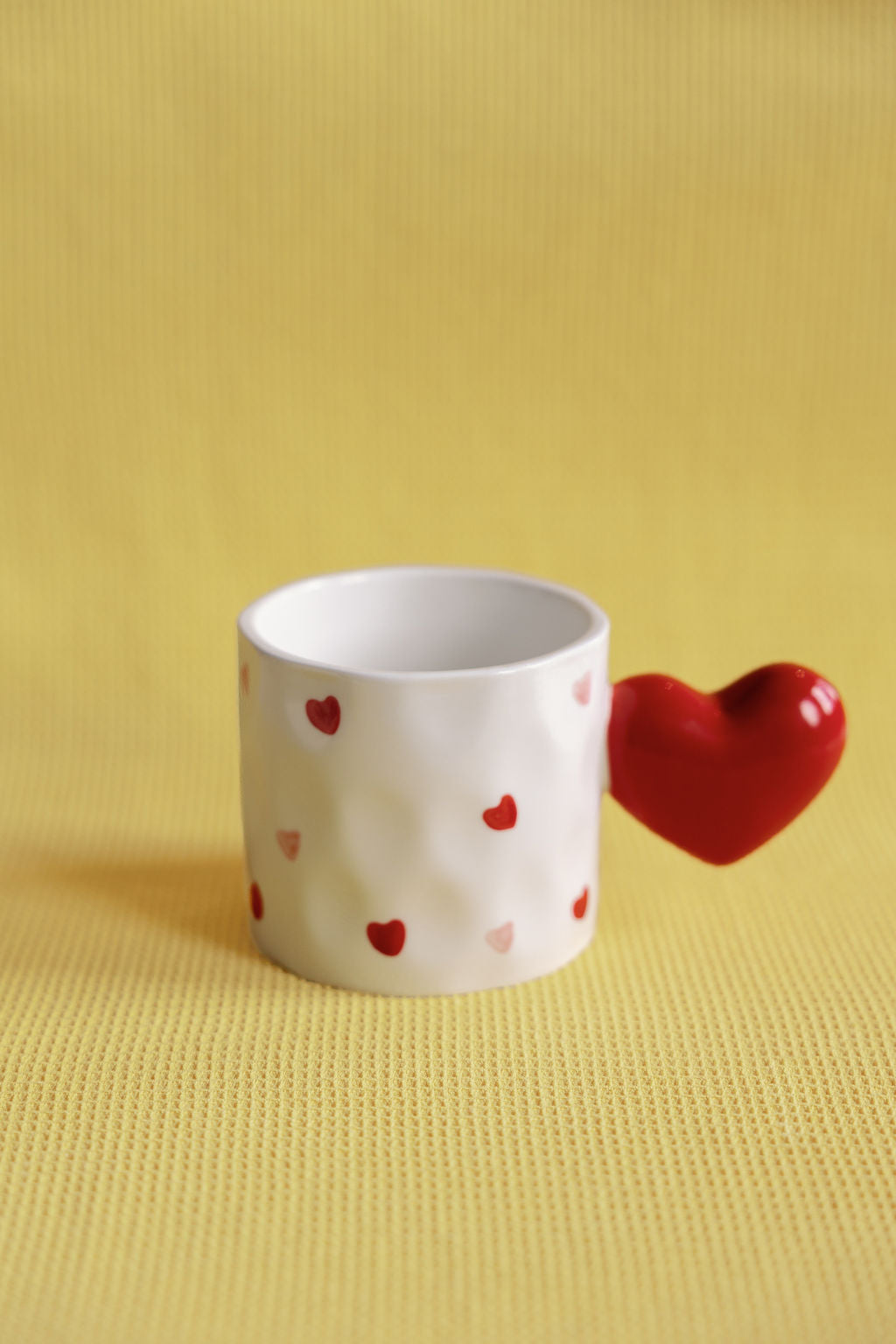 Sweetheart ceramic mug with scattered red hearts and a sculptural red heart-shaped handle.