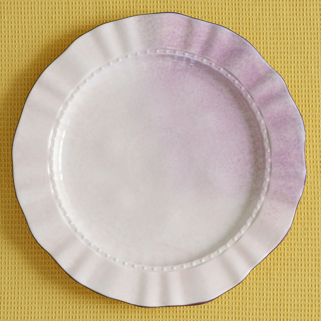 Round white plate with purple rim on a yellow textured background