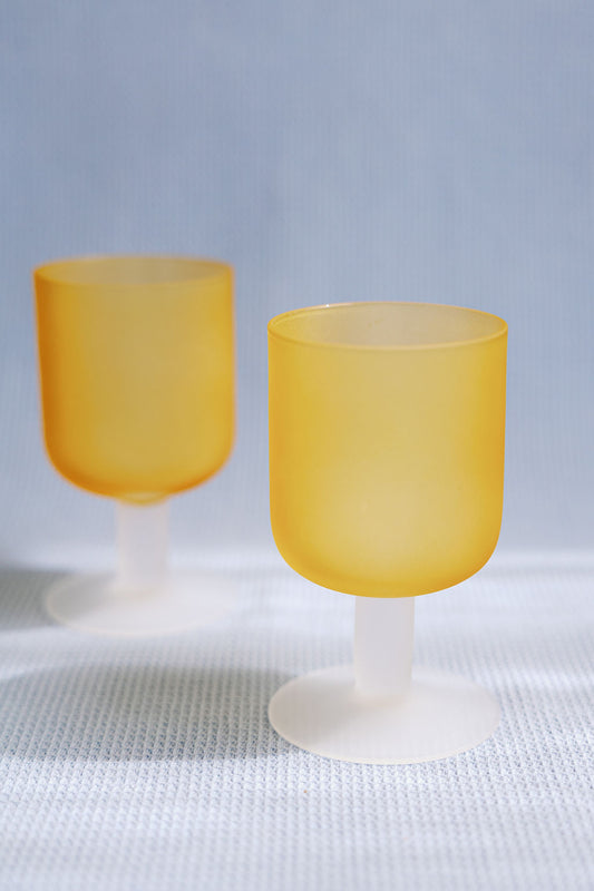 Two frosted amber Sea Glass stemmed goblets with white stems on a textured white cloth, full product shot.
