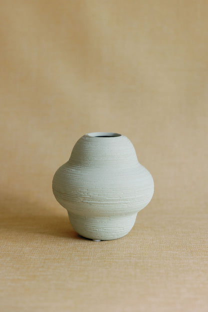 Green ceramic vase on a beige background