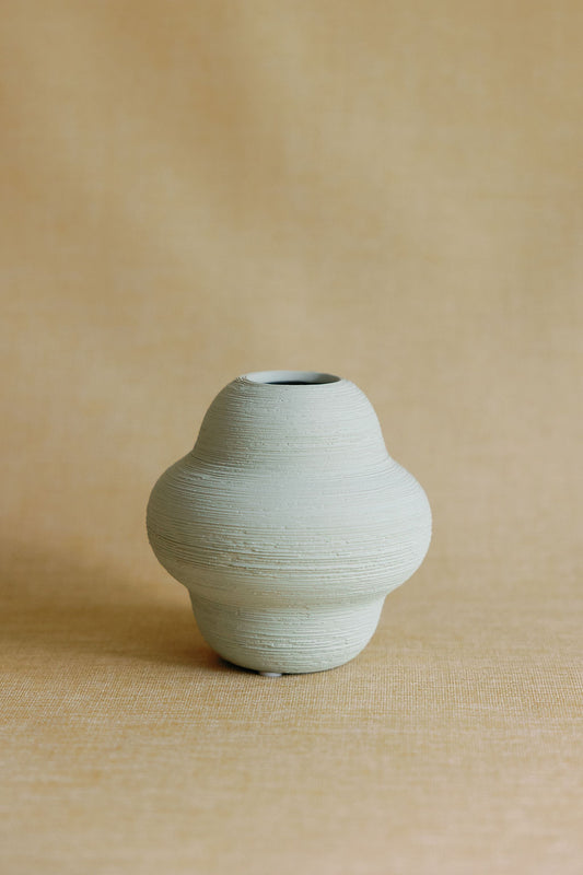 Green ceramic vase on a beige background