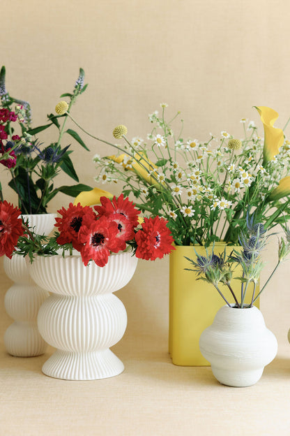 Vases with flowers on a beige surface