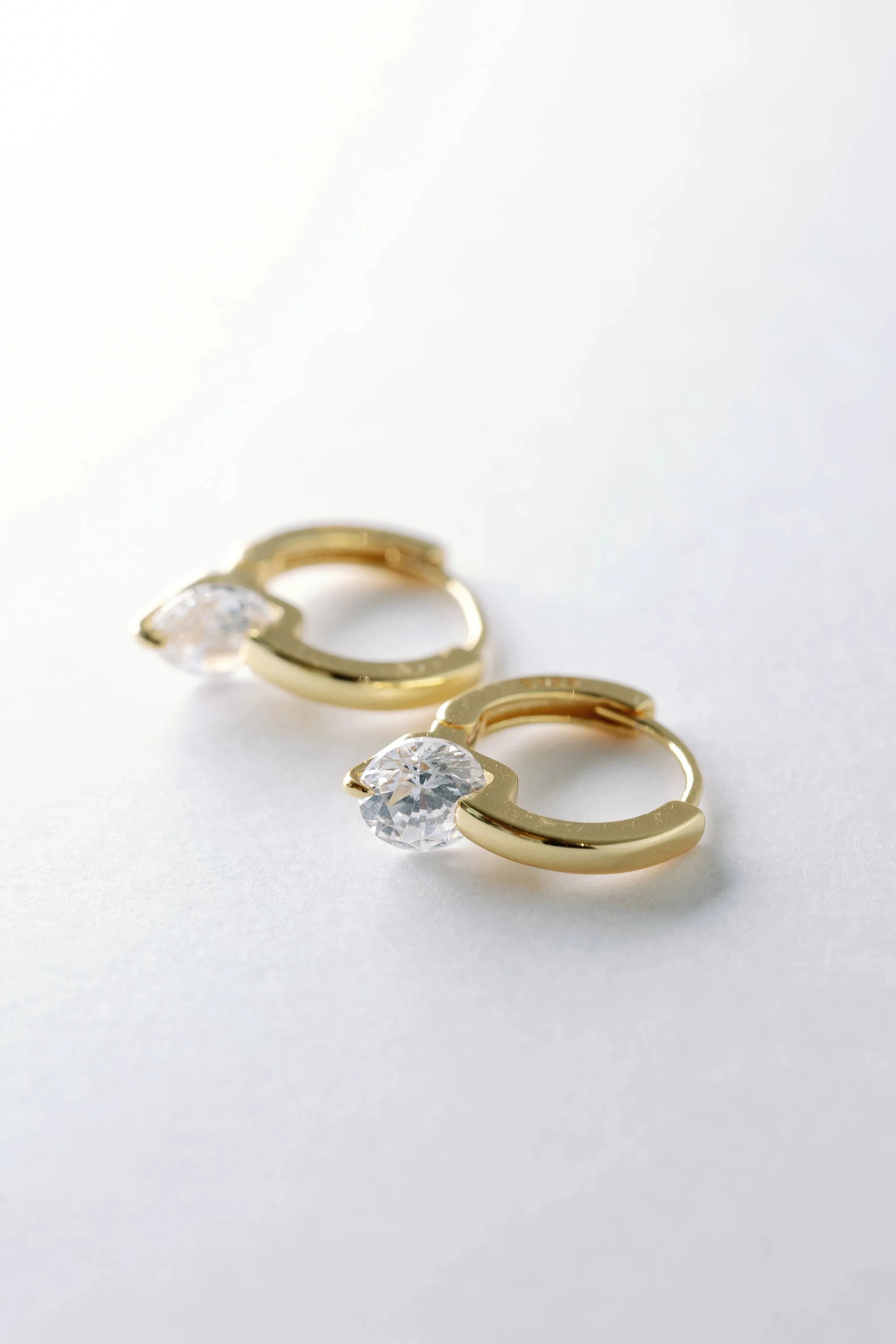Gold floating crystal huggie earrings angled close-up, round crystals spanning the polished hoops