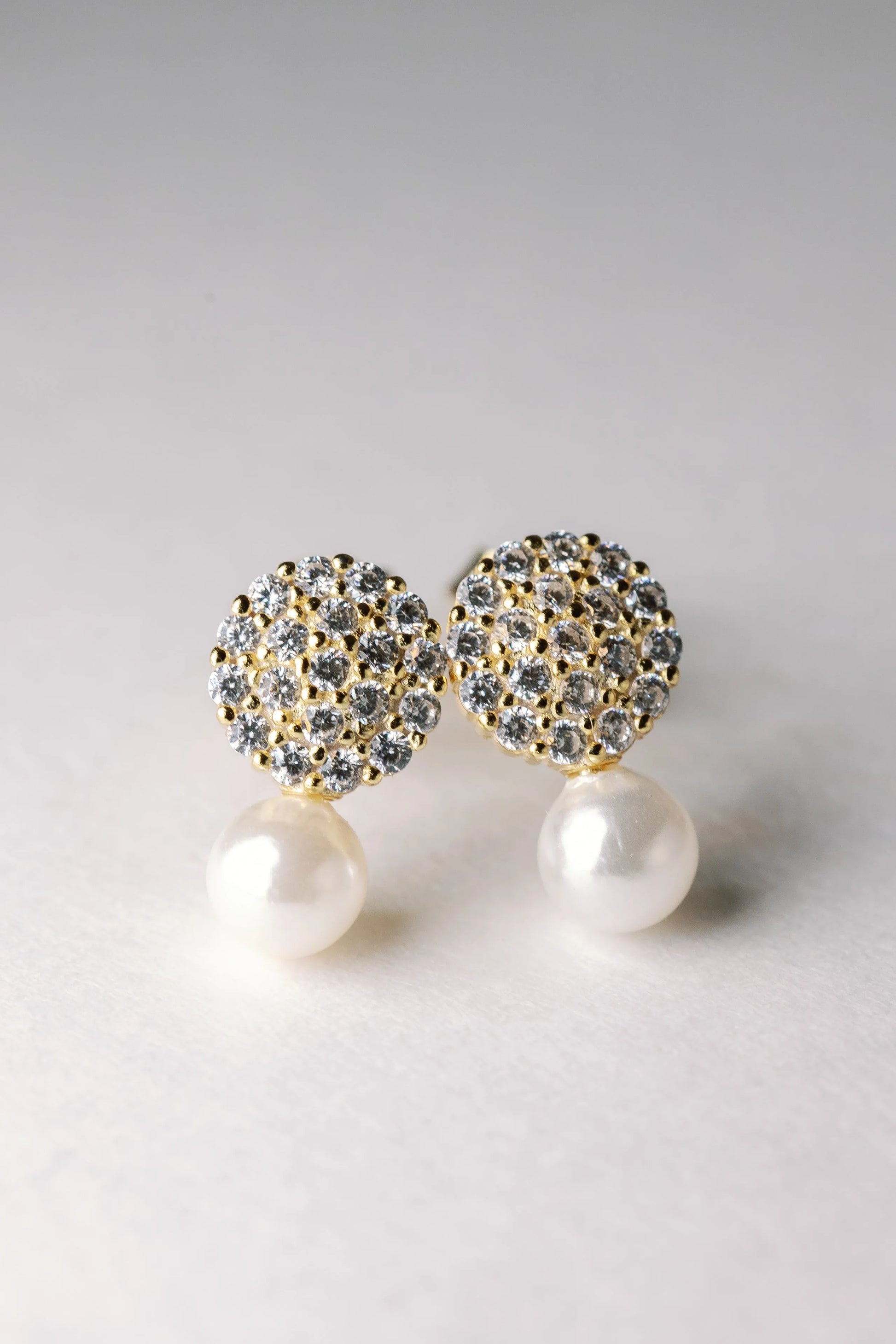 Gold Starlight & Pearl studs with crystal-paved domes and large white pearl drops, close-up
