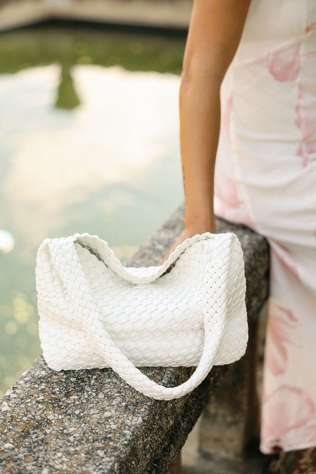 White textured handbag on a stone surface with a blurred natural background
