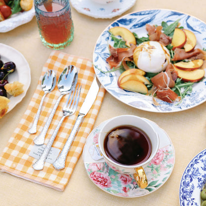 Table setting with plates of food, cups, and cutlery on a yellow tablecloth.
