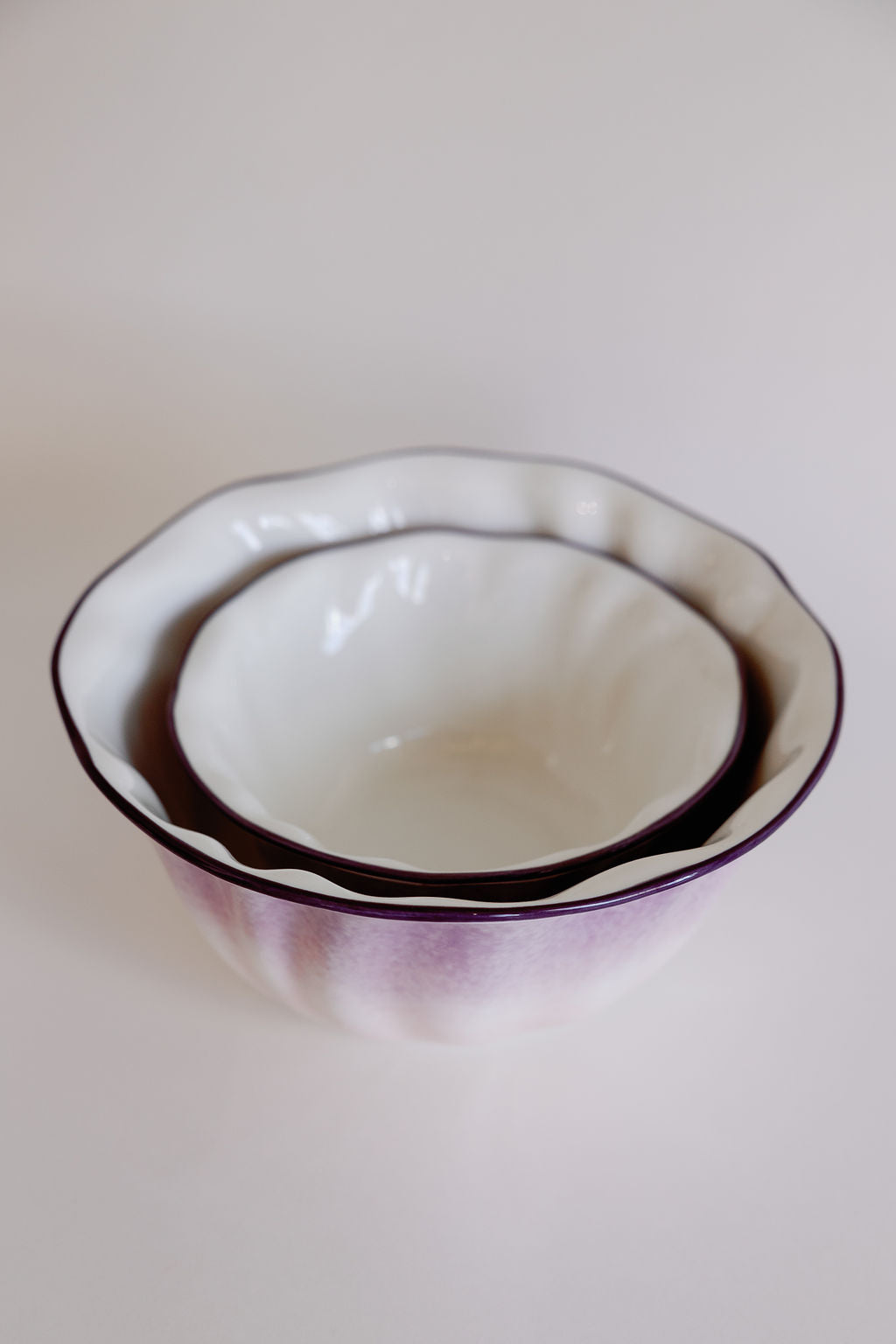 Two lavender ombre ruffle salad bowls nested, scalloped rims with deep purple edge fading to white.