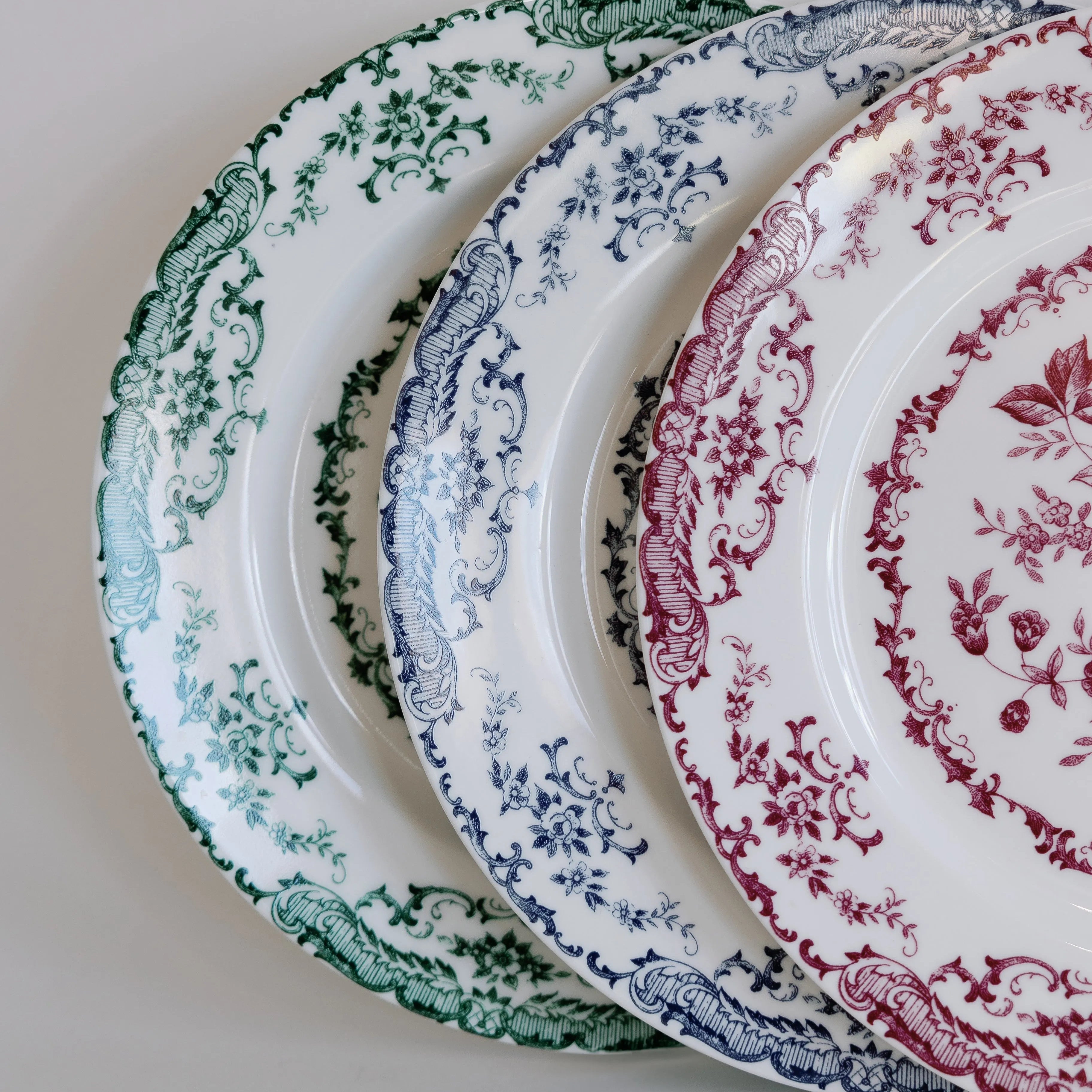 close up of floral pattern porcelain plates with magenta, navy, and forest green patterns