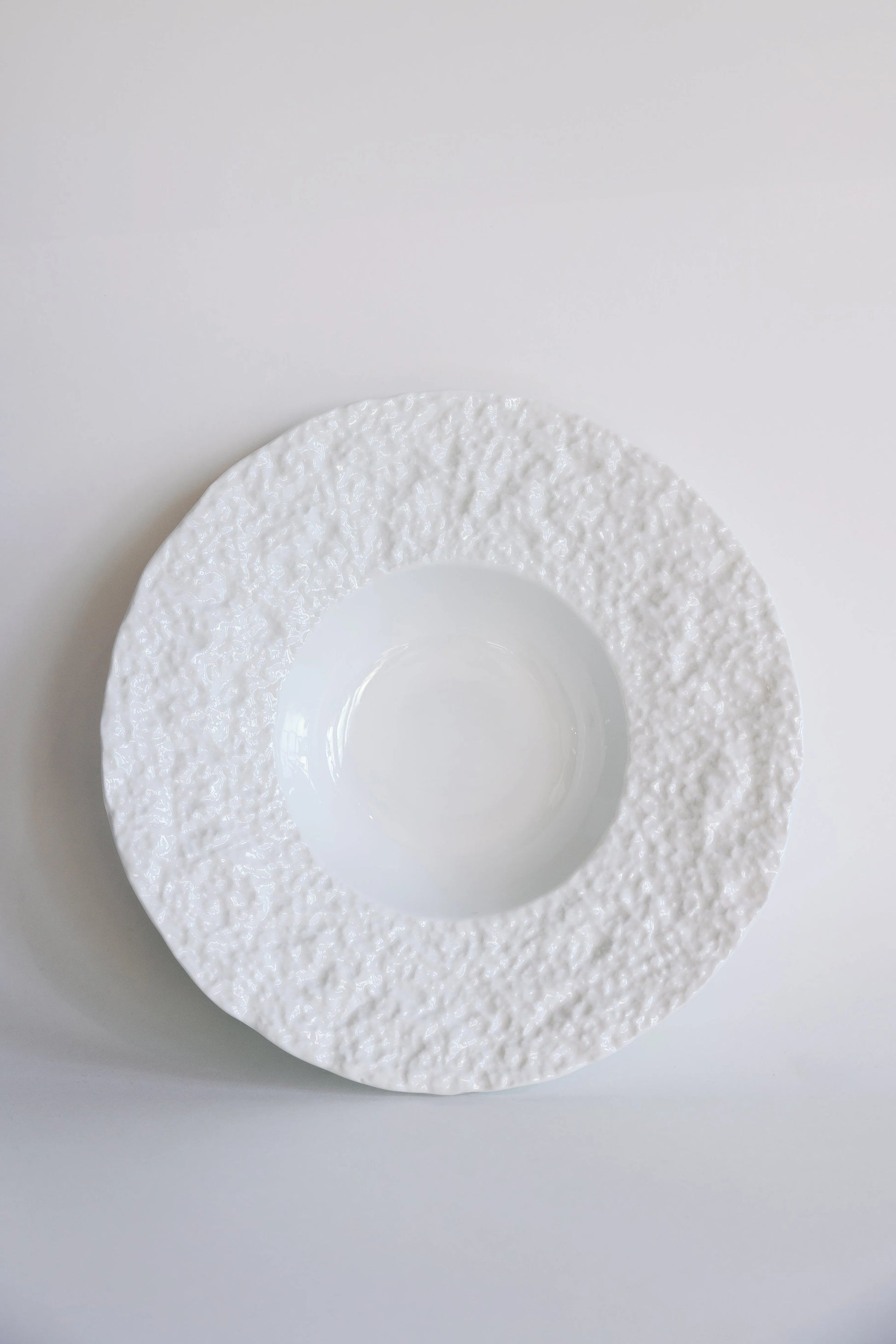 White textured bowl with wide snowy pebbled rim and deep glossy center, overhead view