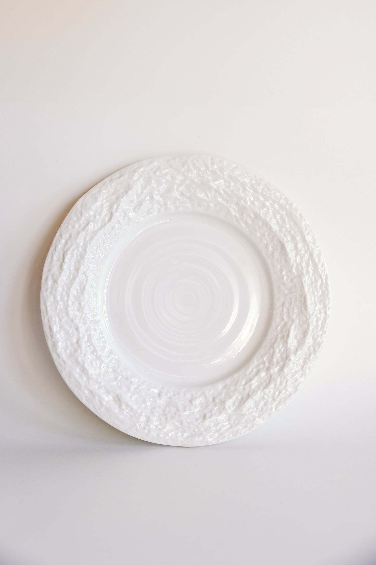 White Alpine Snow porcelain dinner plate with textured crackled rim and swirled center on a pale background.