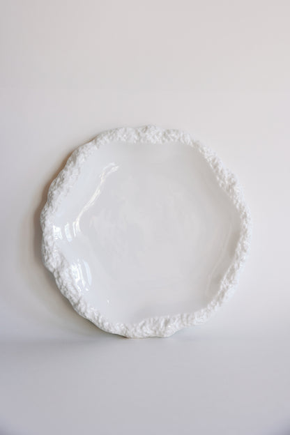Amalfi white porcelain dinner plate with a textured organic rim, shown flat from above on a white backdrop.