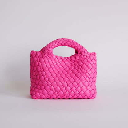 hot pink woven handbag on a light gray background