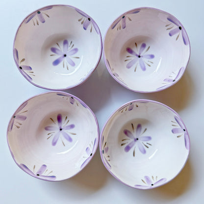 Set of four lilac orchid porcelain bowls overhead, each with hand-painted purple floral motifs inside.