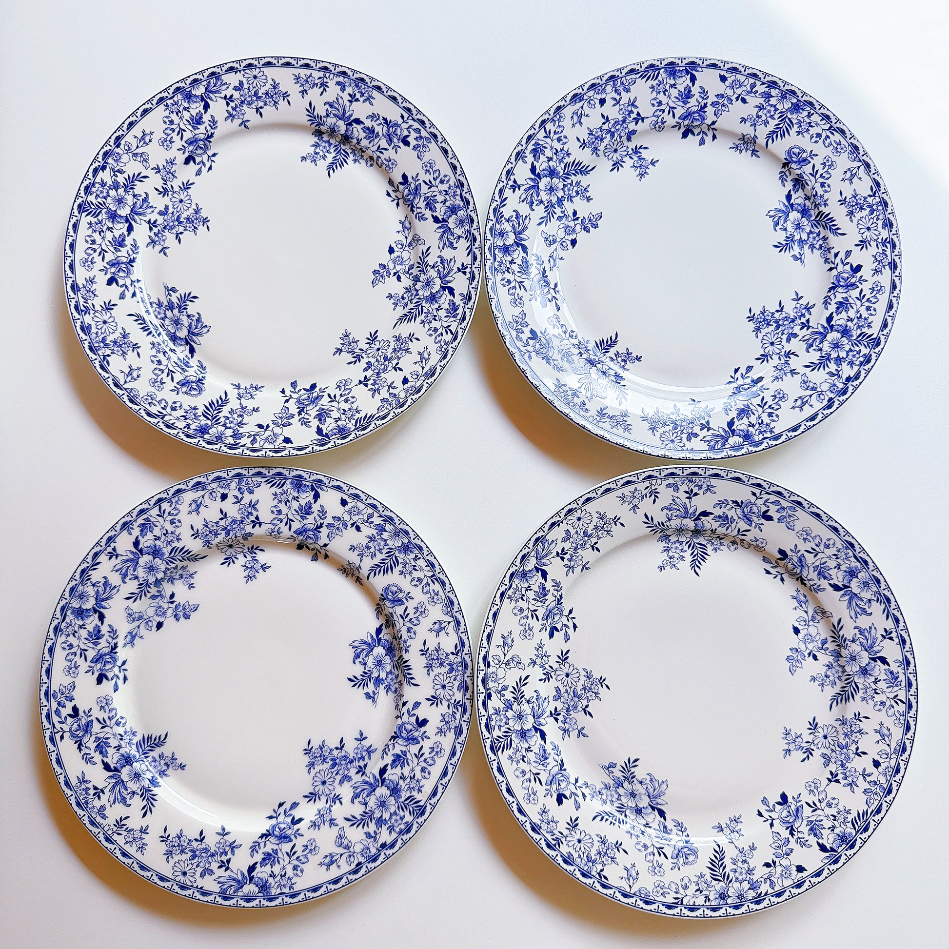 Four blue and white floral-patterned plates on a white background