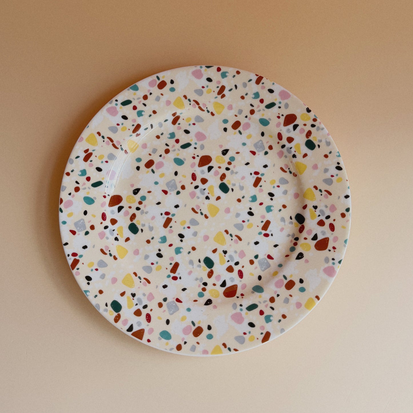 Round plate with multicolored speckled pattern on a beige background