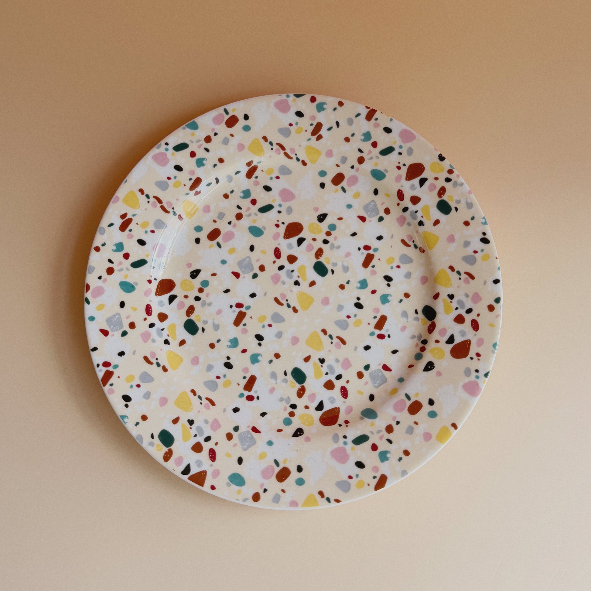 Round plate with multicolored speckled pattern on a beige background