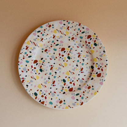 Round plate with multicolored speckled pattern on a beige background