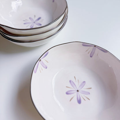 Set of white ceramic bowls with purple floral patterns on a light background